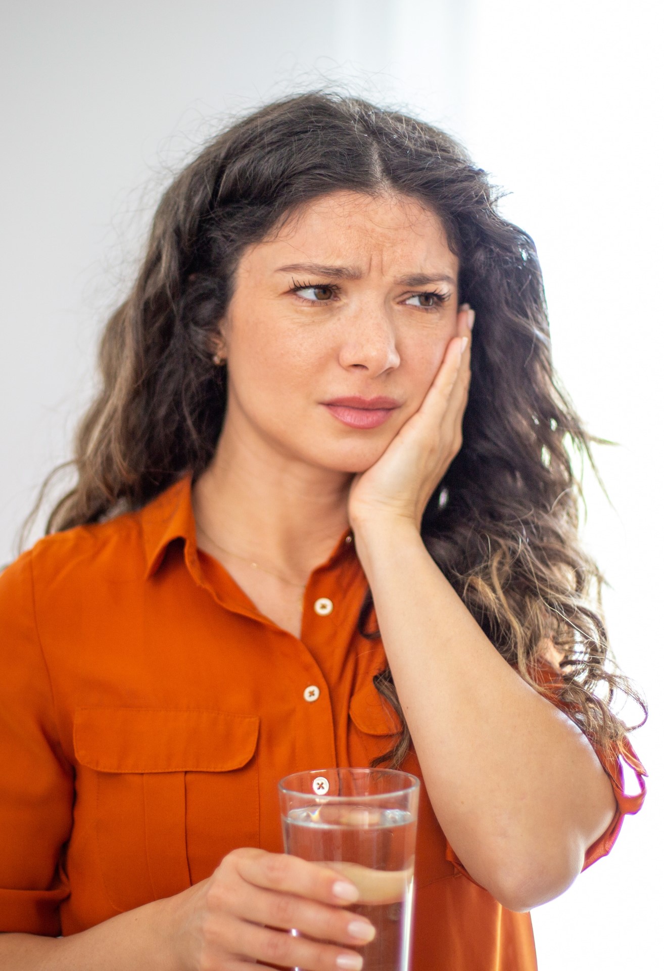 Young women holding her face as if with a painful toothache.