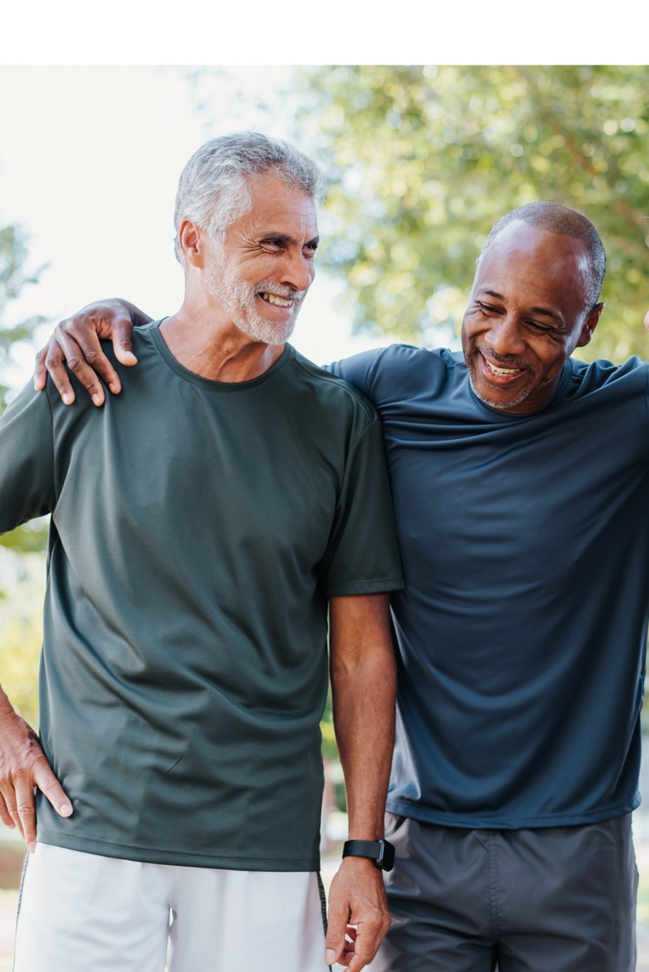 Two middle aged men smiling and walking outdoors together.