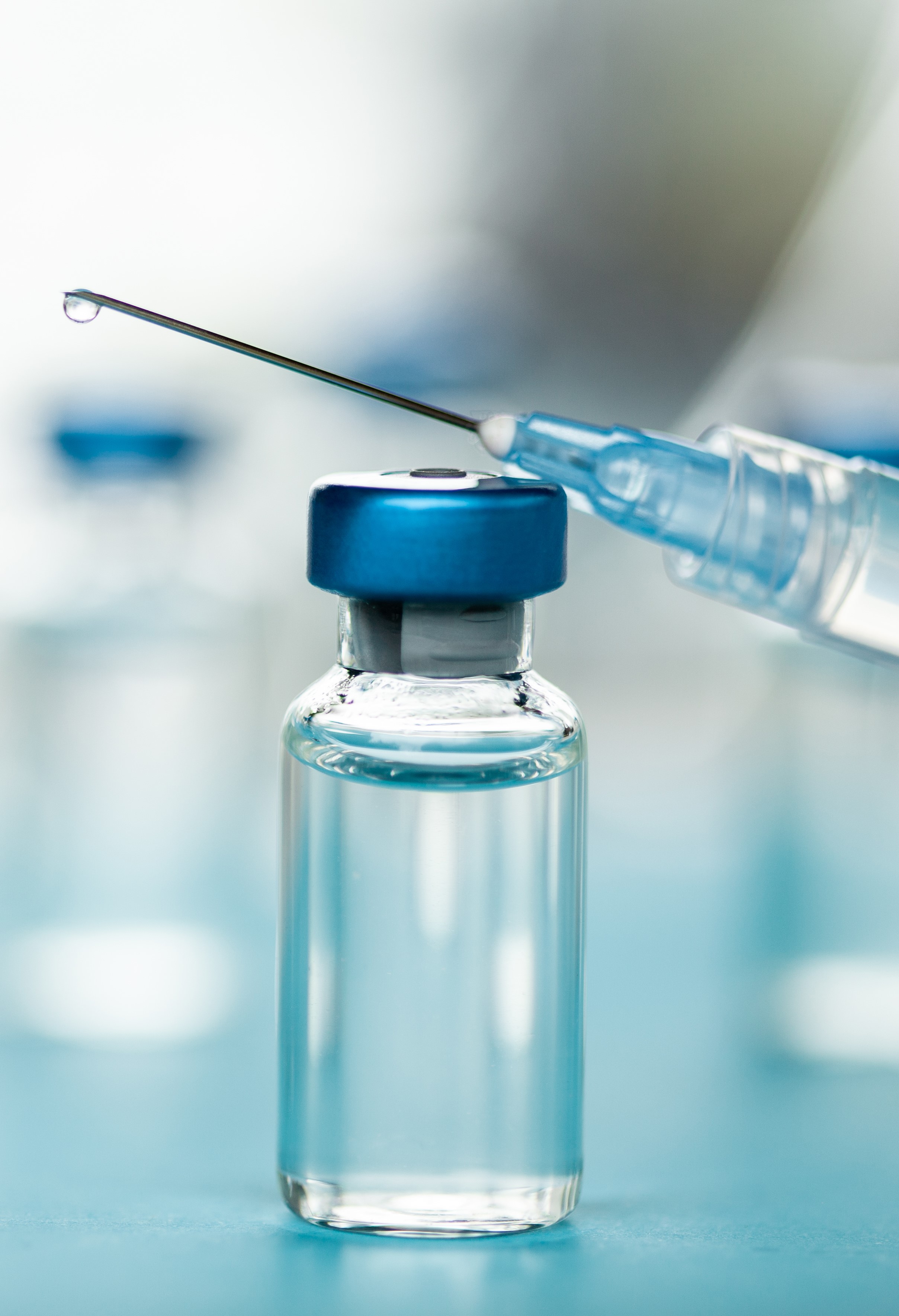 Small syringe and vial in blue tones on lab bench