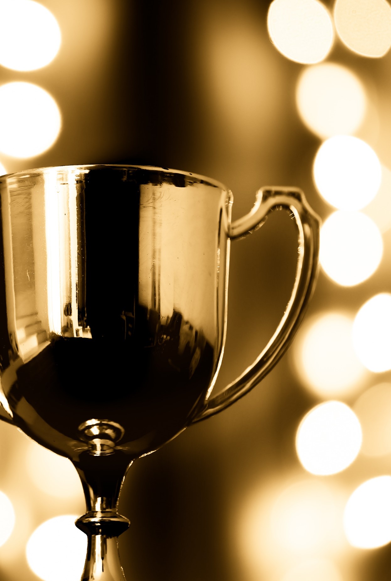 Gold trophy against an glittering golden backdrop
