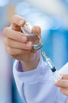 A vaccine being drawn from a bottle with a syringe