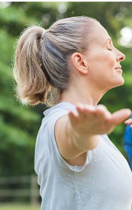 Middle aged woman doing yoga in park with eyes closed